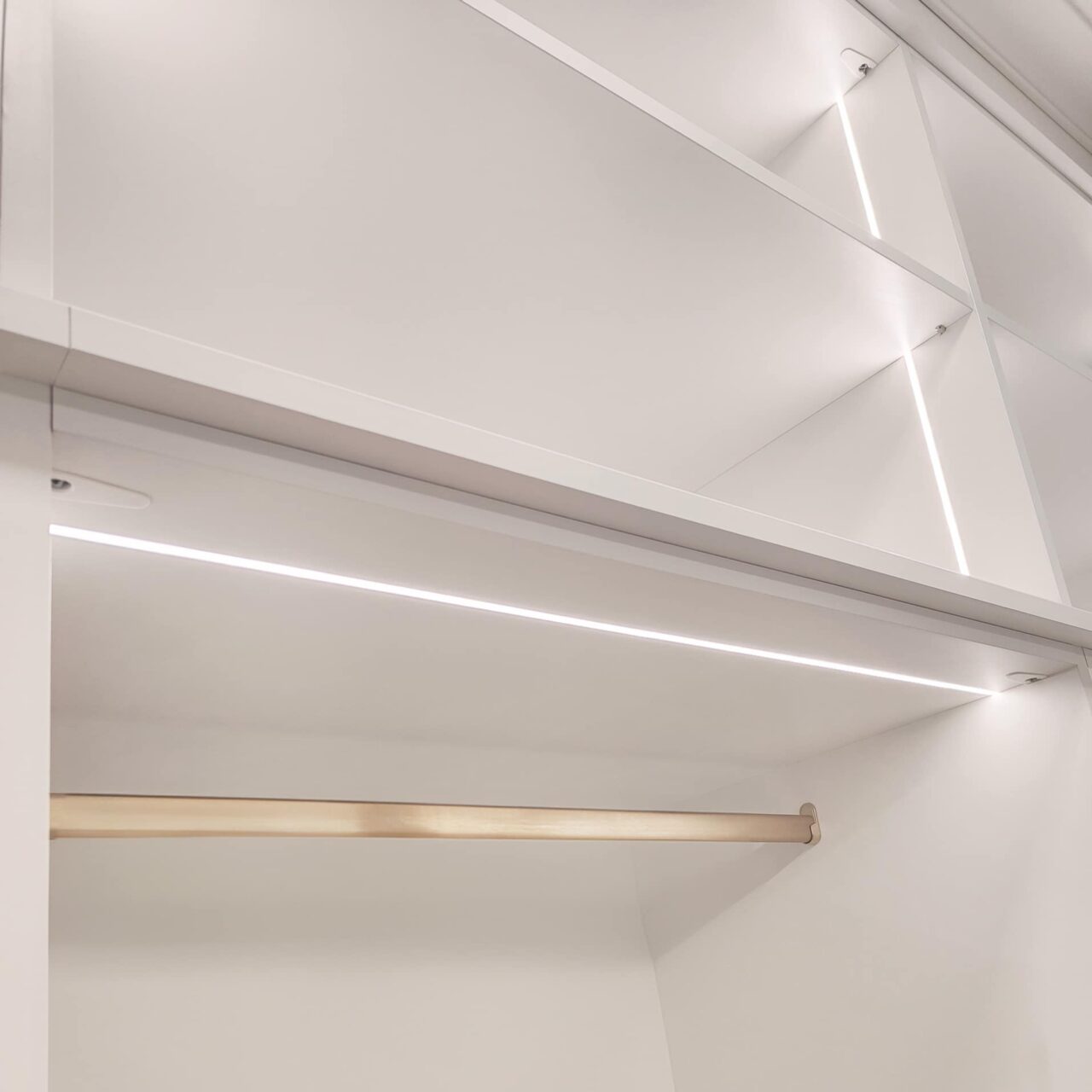 Close-up view of elegant lighting fixtures illuminating custom shelving in a walk-in closet