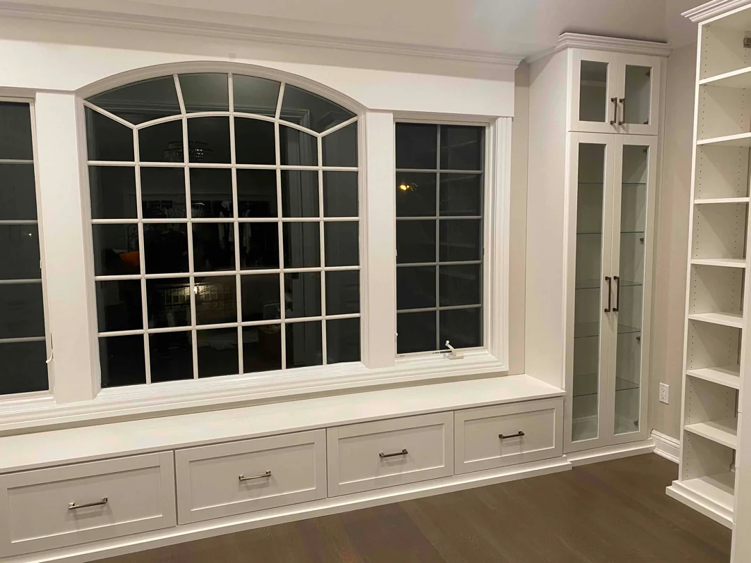 A good balance is about 40% open display. This gives the built-in personality without making the living room storage feel crowded. In this design, the window bench, drawer storage, glass cabinets, and open shelves work together to create a finished focal point around the window.